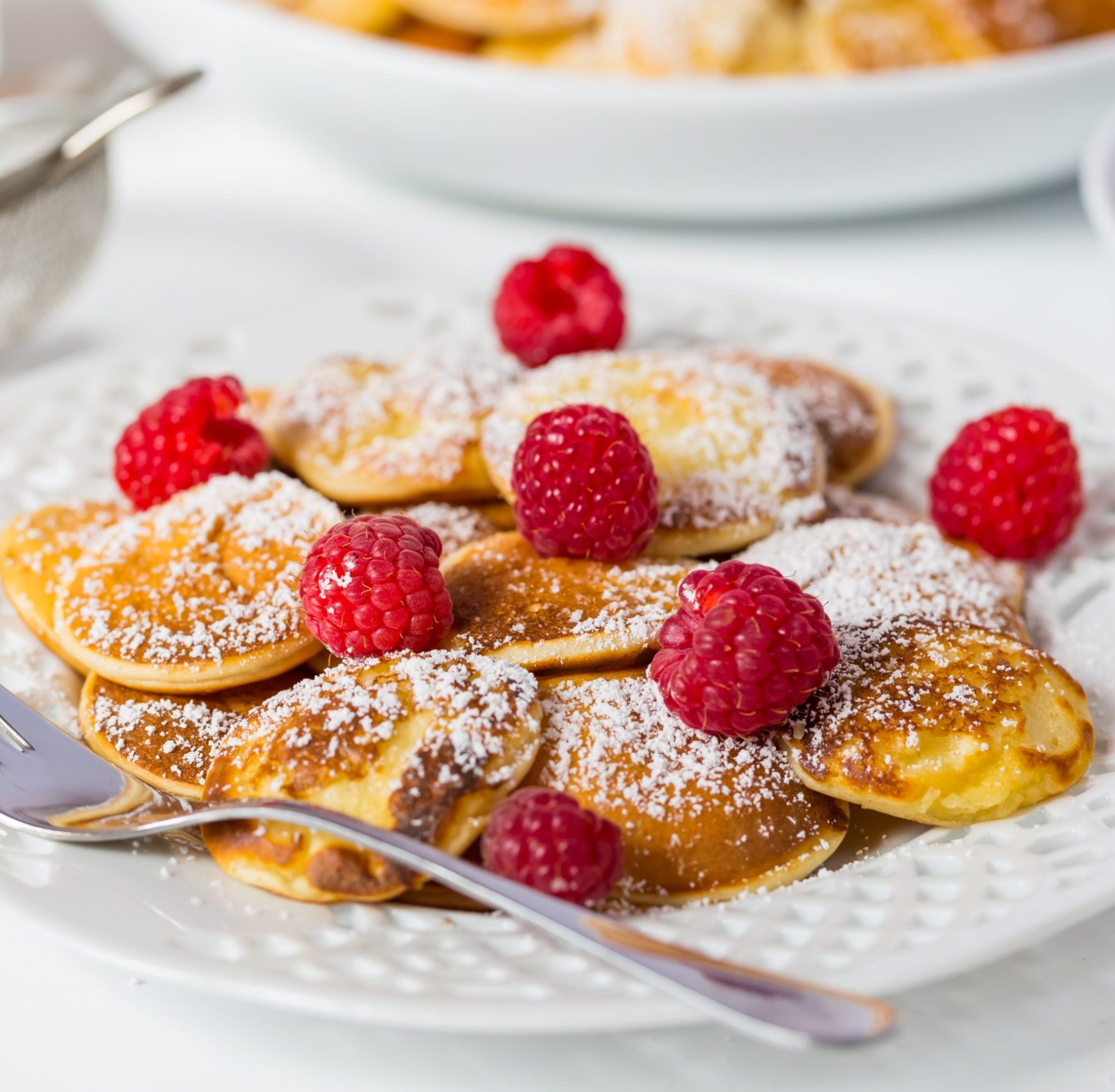 Poffertjes - small Dutch pancakes with fresh raspberries. Traditional Dutch cuisine.